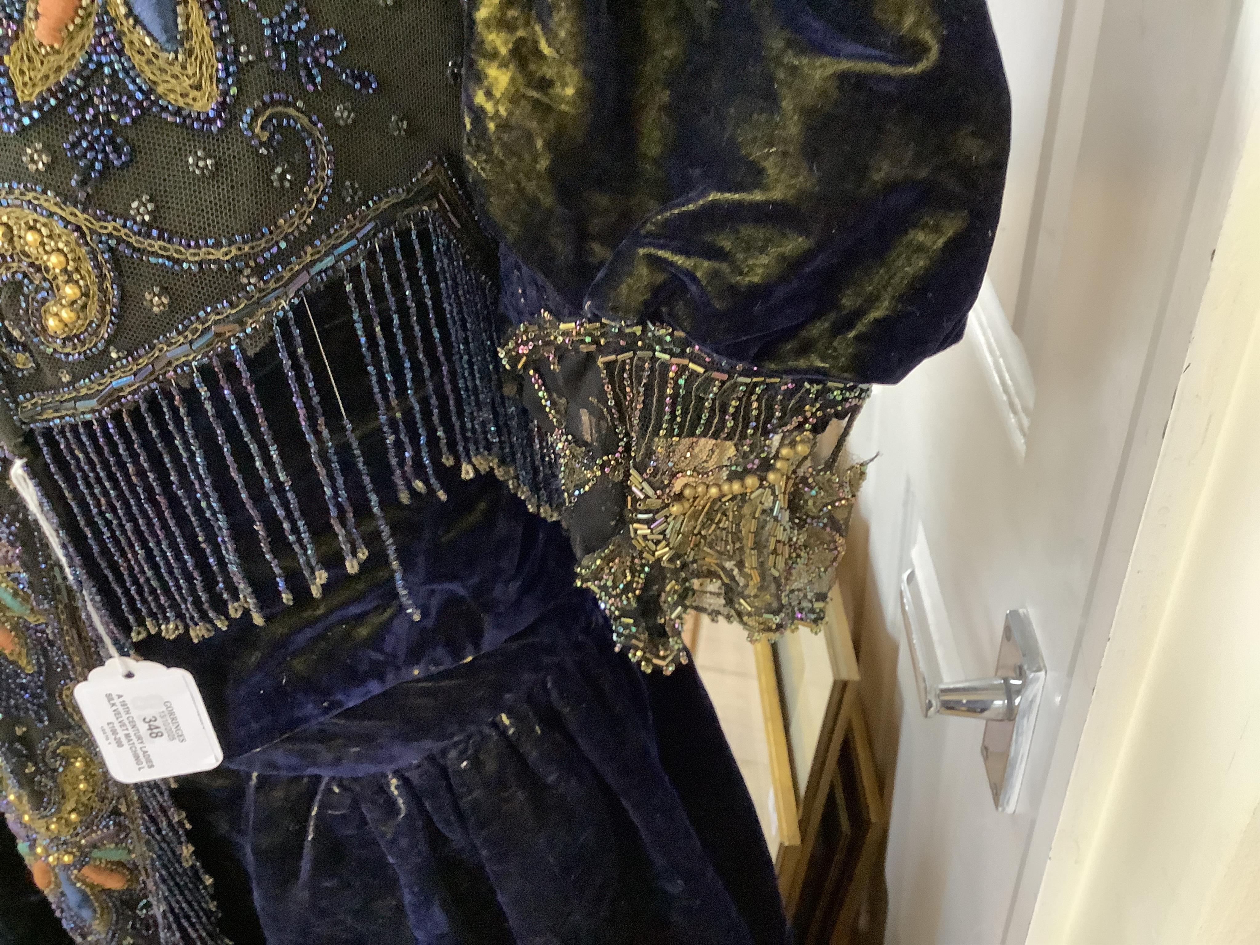 A 19th century ladies silk velvet matching long sleeved jacket/bodice, and skirt, together with another matching short sleeved bead worked bodice and white feather headdress.(4). Cape 106cm long. Condition - Both bodices